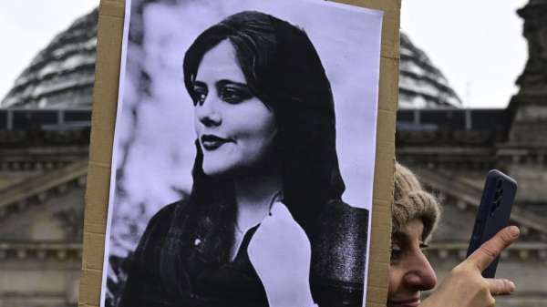 A woman takes a selfie as she holds a portrait of Mahsa Amini during a demonstration in front of the German lower house of parliament on International Women's Day, on 8 March 2023