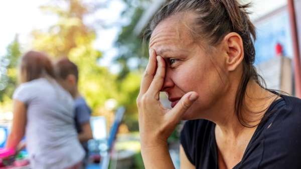 Woman with hand over face looks distressed