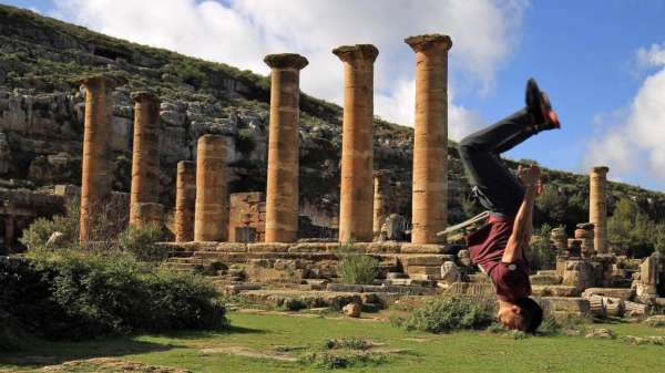 في شرق ليبيا ، شاب يؤدي حركات من رياضة الباركور بين أنقاض مدينة سيرين العائدة إلى زمن اليونان.