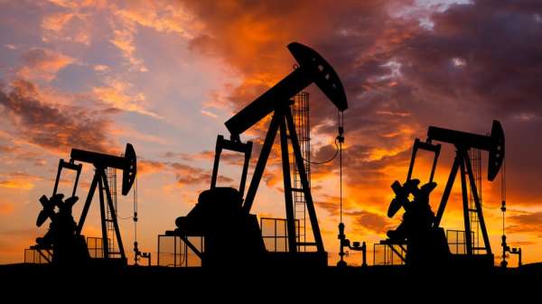 Oil field with rigs and pumps at sunset