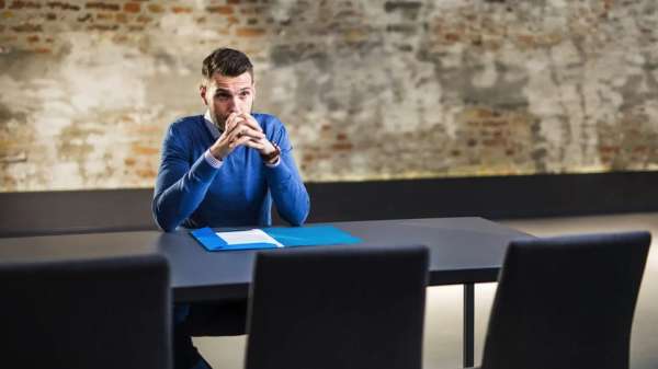 Man sits at desk thinking