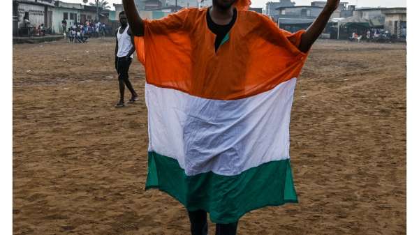 أحد مناصري الرئيس السابق لوران غباغبو يتوشح بعلم ساحل العاج ويشير بعلامة النصر خلال مسيرة الخميس قبيل عودة غباغبو إلى البلاد.