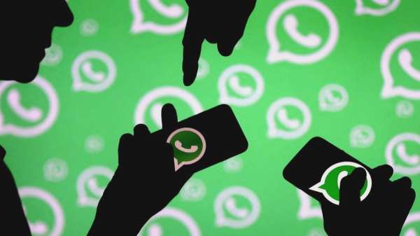 رجال يقفون مع هواتفهم الذكية أمام شعار واتساب